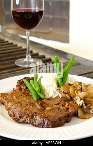 Ribeye cuit riz farine de haricots verts et de champignons close up avec du vin rouge hors focus Banque D'Images