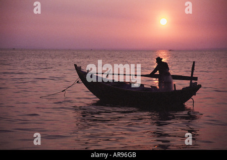 Sur son bateau de pêcheur au coucher du soleil Banque D'Images