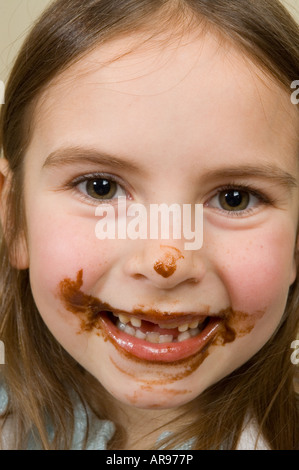 La petite fille visage recouvert de chocolat après cuisson Banque D'Images