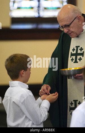 L'Archevêque Daniel Pilarczyk de l'Archidiocèse de Cincinnati, Ohio offrant la communion d'un jeune garçon (caucasien) paroissien Banque D'Images