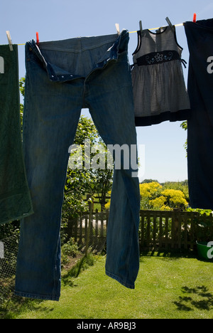 Image d'une paire de jeans grande accrochée à un lave-ligne à côté d'une petite robe bébé Banque D'Images