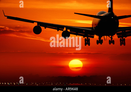Boeing 747 jumbo jet airliner battant l'atterrissage dans un golden orange cloud sky at sunset Banque D'Images