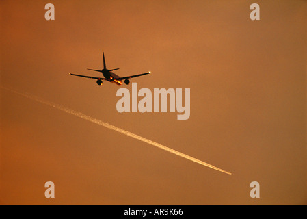 Boeing 757 avion de ligne volant à altitude de croisière et d'une traînée de vapeur au crépuscule coucher de soleil golden orange sky Banque D'Images