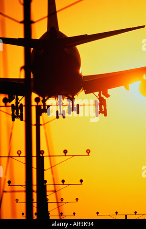 Avion de Boeing 747 jumbo jet en l'air avec le train roulant vers le bas l'atterrissage dans un golden orange cloud sky at sunset Banque D'Images