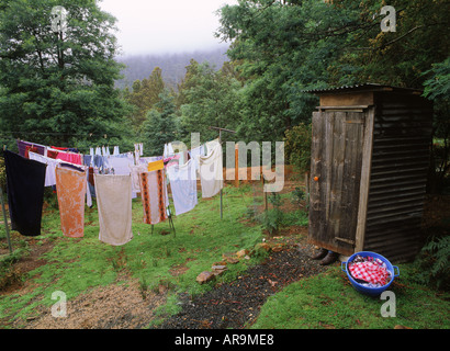 Personne assise dans le vieux jardin en bois ou dunny outhouse en regard de la ligne chiffons en Tasmanie Banque D'Images