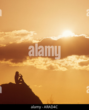 Girl relaxing hippie seule sur une colline au coucher du soleil Banque D'Images