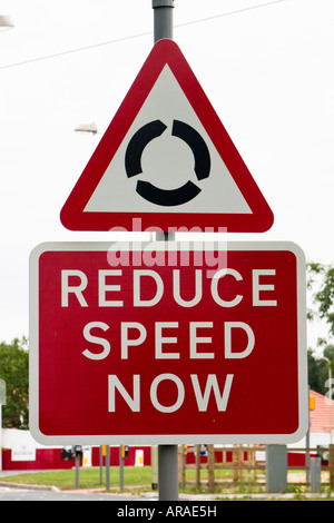 Réduire la vitesse maintenant rond-point devant road sign Banque D'Images