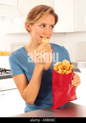 GIRL EATING POTATO CHIPS OU CHIPS Banque D'Images