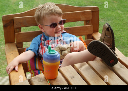 Trois ans qui posent avec des lunettes de soleil et les pieds sur la table Banque D'Images