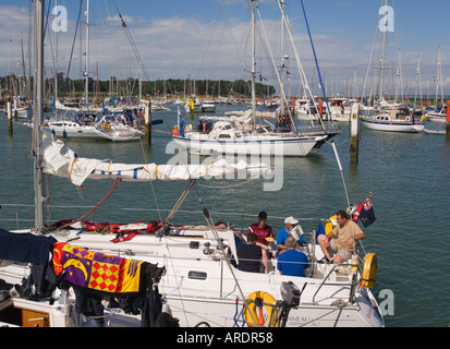 Les gens se détendre assis sur la poupe du yacht dans le port de Yarmouth avec d'autres bateaux de luxe amarré à l'île de Wight en Angleterre Banque D'Images