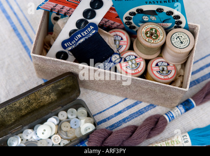 Les boutons utilisés et recyclés dans un vintage tin avec une boîte de bobines de coton, pressstuds et crochets et oeillets Banque D'Images