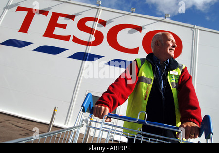 Un homme âgé poussant un chariot sous-un magasin Tesco à Ilfracombe, Devon, UK Banque D'Images