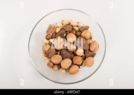 Divers types de noix dans des coquilles dans le bol en verre de dessus découpe aérienne isolé sur fond de table blanc personne horizontal haute résolution Banque D'Images