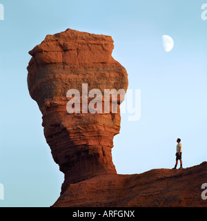 Un touriste près du rocher de l'érosion et la Lune dans Khermen Tsav Canyon au coucher du soleil. Parc National Gurvansaikhan, désert de Gobi Mongolie Banque D'Images