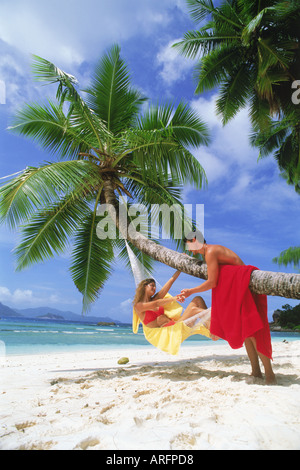 Couple avec hamacs et serviettes colorées sur La Digue aux Seychelles Banque D'Images