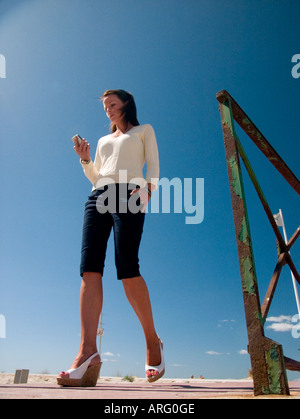 Un low angle view of young woman walking towards camera vérifier ses messages sur son Blackberry Banque D'Images