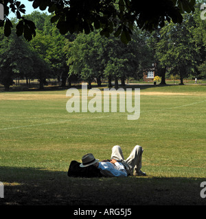 L'homme dormant dans l'ombre du parc. Le modèle ne libération requise : distance, le dos tourné rend l'homme méconnaissable Banque D'Images