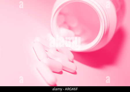 Les petits comprimés médicinaux blanc de renverser une bouteille avec des femmes rose tonifiant à thème Banque D'Images