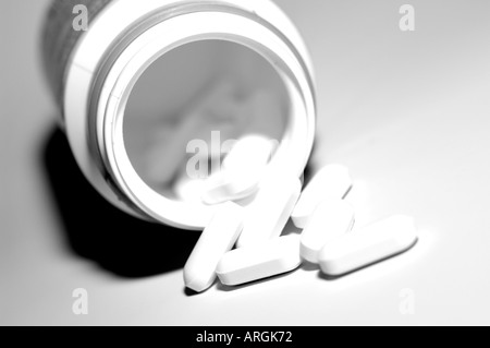 Les petits comprimés médicinaux blanc une bouteille de déversement Banque D'Images