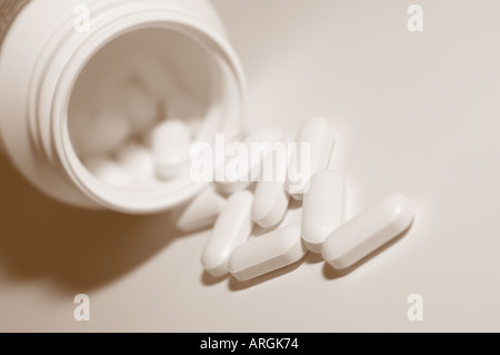 Les petits comprimés médicinaux blanc une bouteille de déversement Banque D'Images
