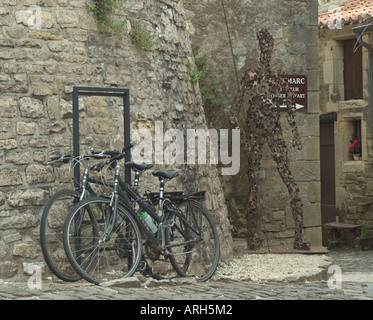 Vélos appuyés contre un mur près d'une sculpture en Cordes sur Ciel Tarn France Banque D'Images