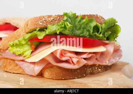 Coupe transversale de pain blanc sandwich avec jambon et légumes sur une planche de bois vue de face gros plan personne horizontal aux États-Unis haute résolution Banque D'Images