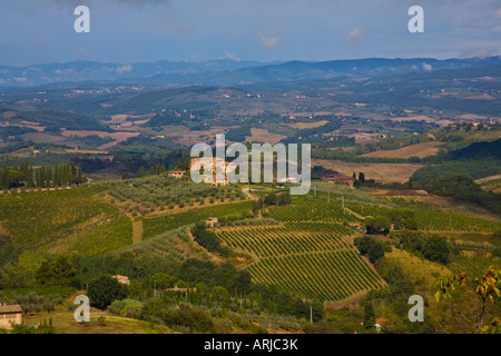 Un centre-gauche villa se trouve au sommet d'une colline en Toscane. Vignes en cascade sur la colline. D'autres collines rouler au loin. Banque D'Images