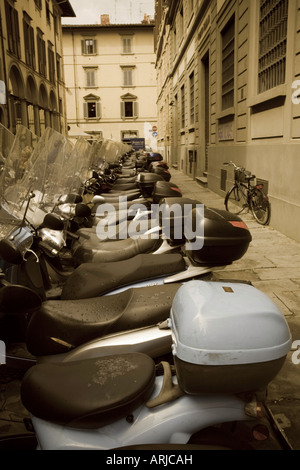 Un scooter de moteur peint en bleu une longue lignée de gardiens les scooters similaires dans une rue. La pédale d'un vélo est garé à proximité. Banque D'Images