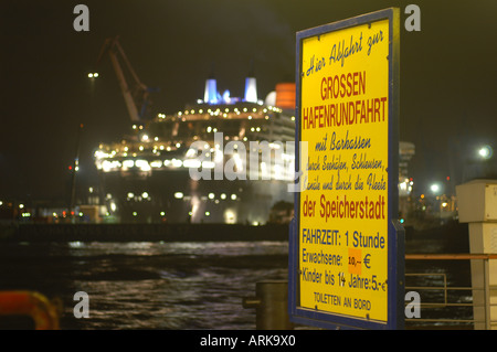 Un signe pour les touristes de prendre un voyage sur un bateau de croisière au port, dans l'arrière-plan le Queen Mary 2 dans la cale sèche d'Elbe 17 de B Banque D'Images