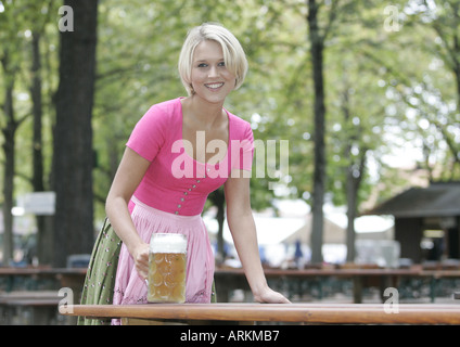 Jeune femme blonde portant une robe dirndl Tegernsee traditionnel dans un biergarten de Munich. Banque D'Images