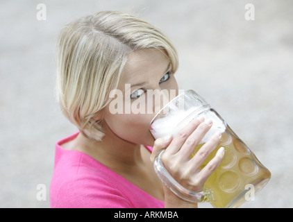 Portrait d'une jeune femme blonde boire une chope de bière. Banque D'Images