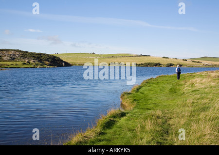 CEMLYN BAY LAGOON avec walker sur l'île d'Anglesey Sentier littoral le long bar de galets au nord du Pays de Galles d'Anglesey Banque D'Images