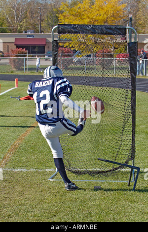 Football player kicking football dans les pratiques un bénéfice net avant de tenter un but ou un point supplémentaire sur le terrain après le toucher des roues Banque D'Images