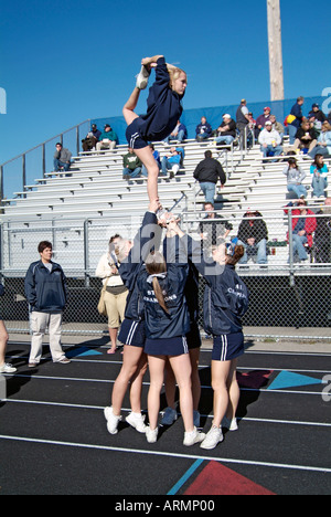 High School cheerleaders complexe et parfois effectuer des manœuvres dangereuses au cours de la présentation à un match de football Banque D'Images