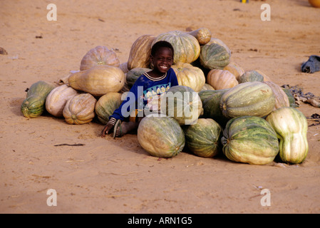 Boubon, près de Niamey, Niger, Afrique de l'Ouest. Garçon nigérien avec squash au marché du fleuve Niger, le port utilisé T-shirt à partir de l'Alaska. Banque D'Images