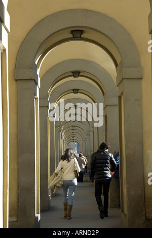 Couple de touristes marcher sous le couloir reliant l'Uffizi Vassari avec le Palais Pitti à Florence, Toscane Italie Banque D'Images