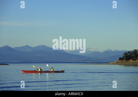 Parksville Beach les pagaies de kayak double sur le détroit de Géorgie. Plage côte à distance en soirée, l'île de Vancouver, Colombie-Britannique, Banque D'Images