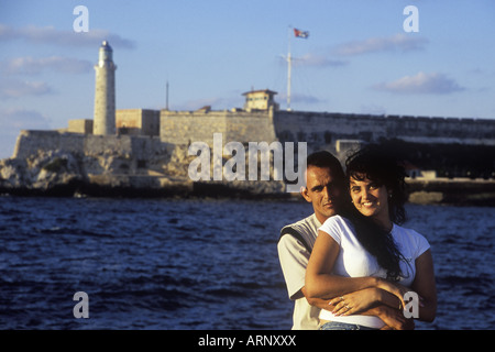 Cuba, La Havane - Couple sur le Malecon, avec Castillo de los Tres Reyes del Morro et de phare derrière Banque D'Images