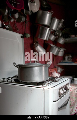 Casseroles pendu sur un mur à une ancienne cuisine avec ancien four et réchaud à gaz Banque D'Images