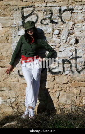 Les jeunes femmes en tenue de combat devant l'abandon du bâtiment en pierre couvert de graffitis Banque D'Images