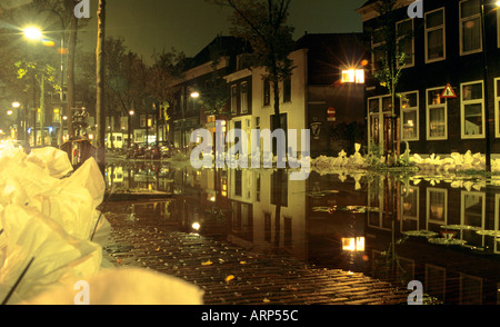 Canal inondé la nuit avec des sacs de sable le long des berges, y compris en premier plan pour empêcher d'autres inondations de rues et maisons pavées. Delft, pays-Bas. Banque D'Images