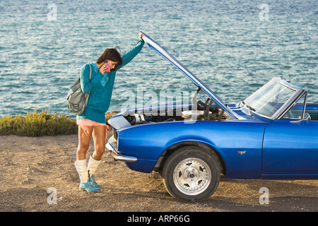 Femme sur téléphone mobile par voiture en panne Banque D'Images