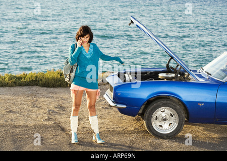 Femme sur téléphone mobile par voiture en panne Banque D'Images