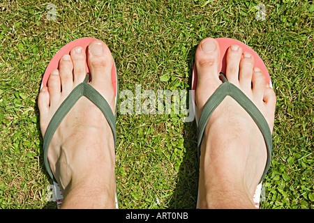 Pieds d'un homme en tongs Banque D'Images