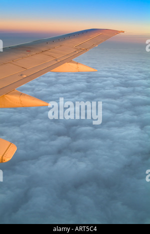 Jet avion battant des ailes au-dessus des nuages à Sunise Banque D'Images