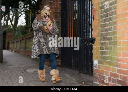 Femme en manteau de fourrure holding stuffed leopard head Banque D'Images