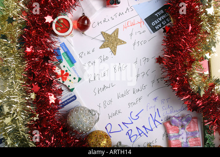 Factures, relevé bancaire, guirlandes, décorations de l'arbre et de carte de crédit entourent une liste de Noël. Banque D'Images