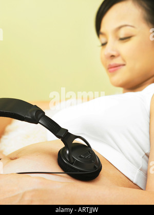 Femme s'amusant avec le casque sur son ventre Banque D'Images