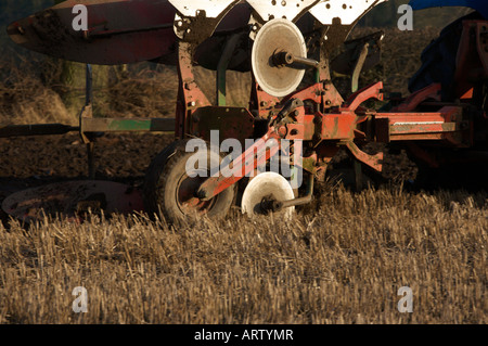 Trois charrue réversible sillon derrière tracteur New Holland de labourer un champ de chaumes prêt à planter de l'orge UK Banque D'Images