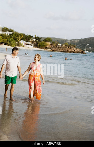 Mature Woman holding un haut la main de l'homme et la marche sur la plage Banque D'Images